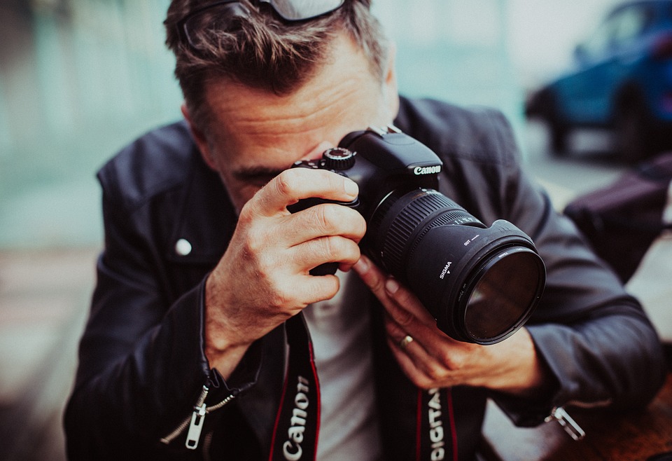Gambar Fotografer Pria Sedang Memotret Menggunakan Kamera DSLR